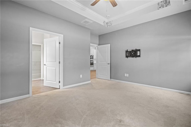 unfurnished bedroom featuring a closet, a spacious closet, crown molding, light carpet, and ceiling fan