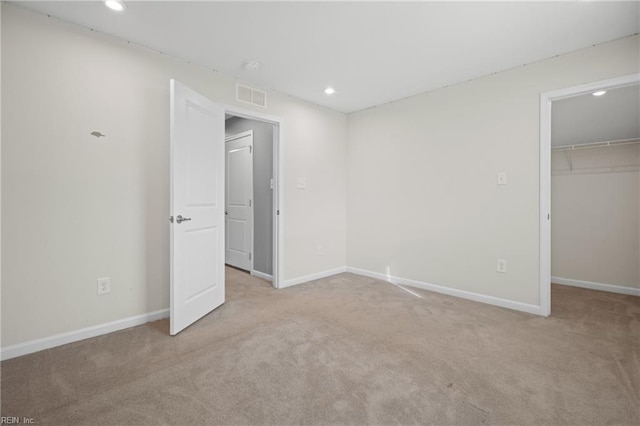 unfurnished bedroom with light colored carpet, a walk in closet, and a closet