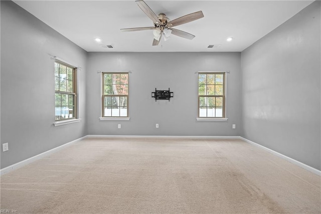 carpeted spare room with ceiling fan and plenty of natural light