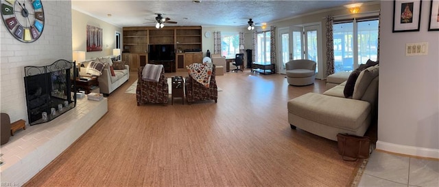 living room featuring a brick fireplace, a textured ceiling, ceiling fan, crown molding, and hardwood / wood-style floors