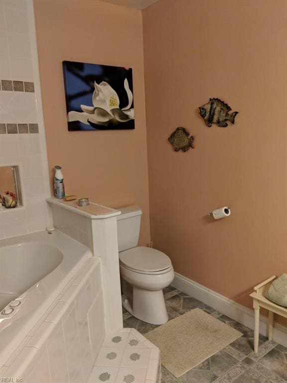 bathroom featuring tiled bath and toilet