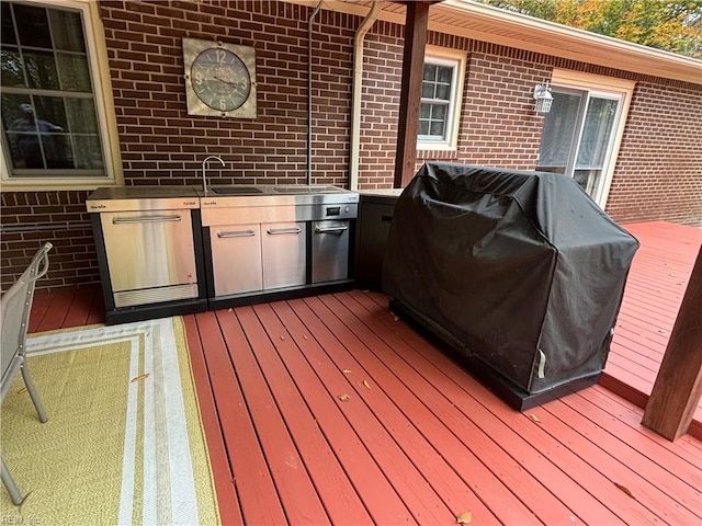 wooden terrace with area for grilling, sink, and grilling area