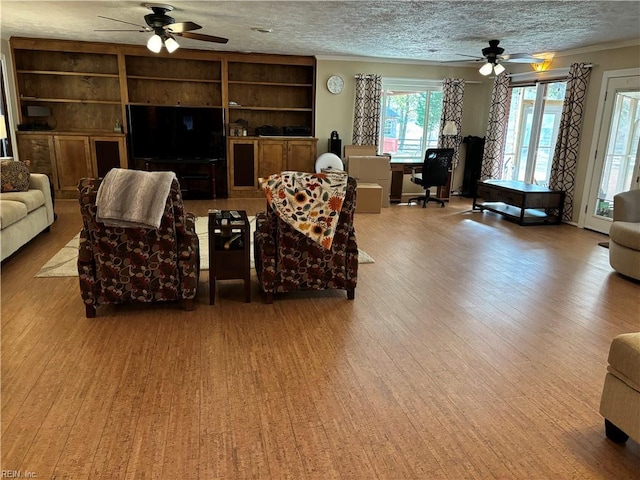 living room featuring light wood-type flooring, a textured ceiling, and ceiling fan