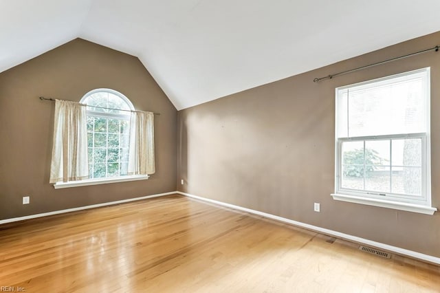 unfurnished room featuring plenty of natural light, wood-type flooring, and lofted ceiling