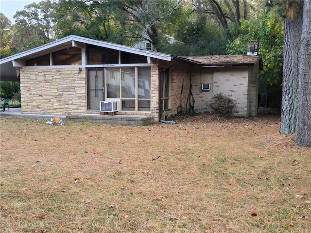 back of property featuring cooling unit, a lawn, and a sunroom