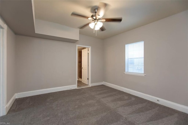 empty room with ceiling fan and dark carpet