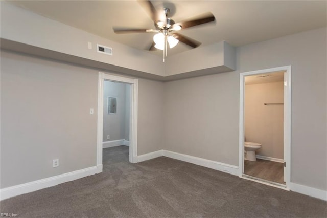 unfurnished bedroom featuring a walk in closet, ceiling fan, connected bathroom, and dark carpet