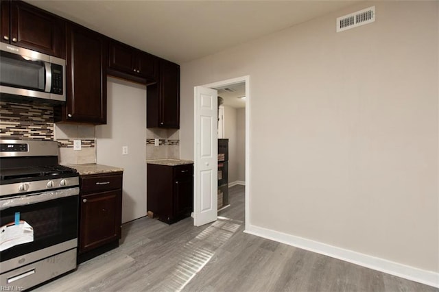 kitchen featuring appliances with stainless steel finishes, decorative backsplash, dark brown cabinetry, and light hardwood / wood-style flooring