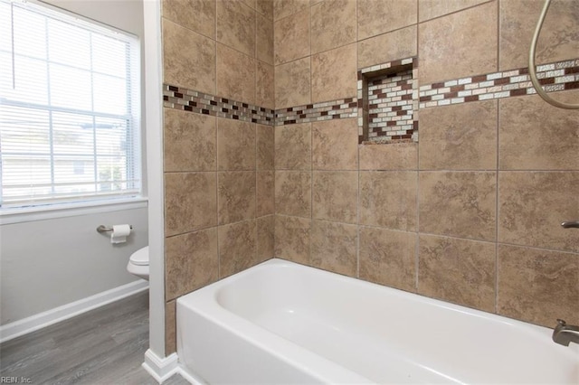 bathroom featuring hardwood / wood-style floors, plenty of natural light, tiled shower / bath combo, and toilet