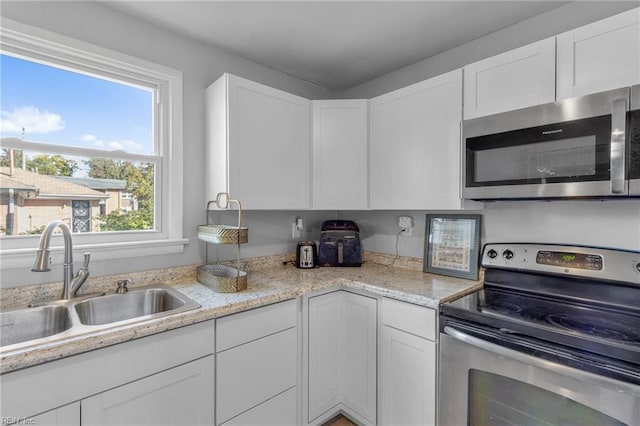 kitchen featuring stainless steel appliances, white cabinets, and sink