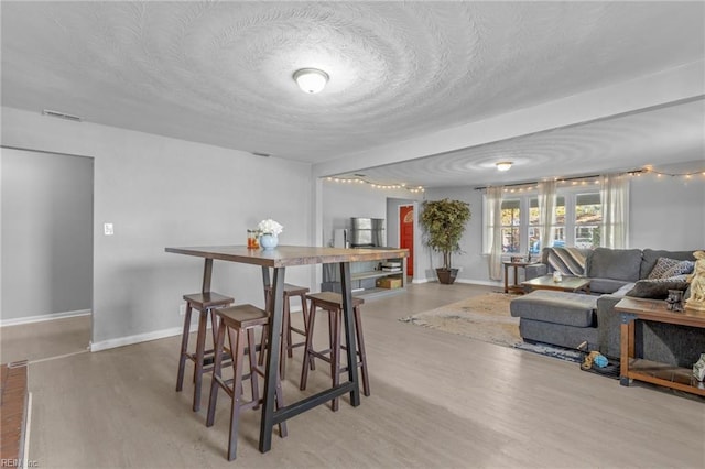 dining space with light hardwood / wood-style flooring and a textured ceiling