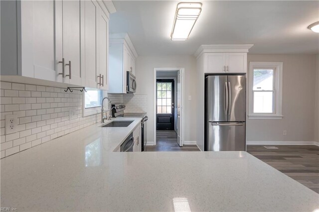 kitchen with light stone countertops, appliances with stainless steel finishes, a healthy amount of sunlight, and dark hardwood / wood-style flooring