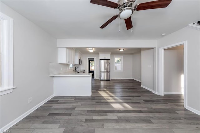 kitchen featuring stainless steel appliances, white cabinetry, backsplash, dark hardwood / wood-style flooring, and kitchen peninsula