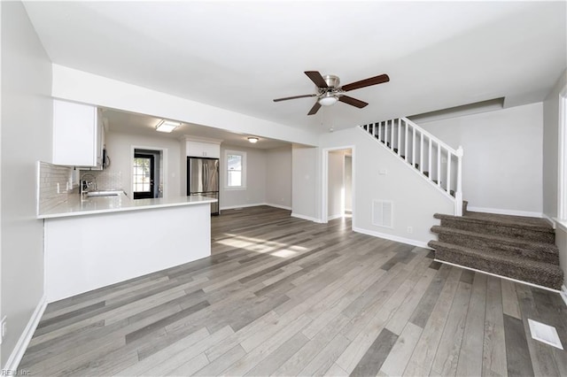 unfurnished living room with hardwood / wood-style floors, sink, and ceiling fan