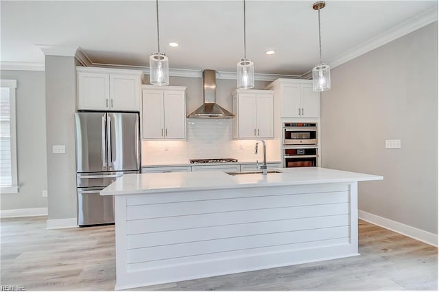 kitchen featuring white cabinetry, wall chimney range hood, appliances with stainless steel finishes, sink, and a kitchen island with sink