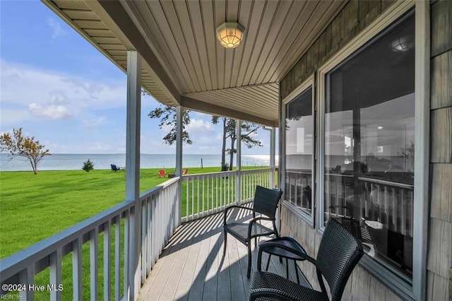 wooden deck with a water view and a lawn