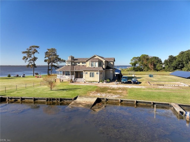 back of property with a water view and a yard