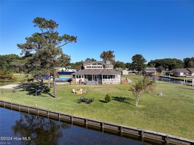 back of house with a water view and a lawn