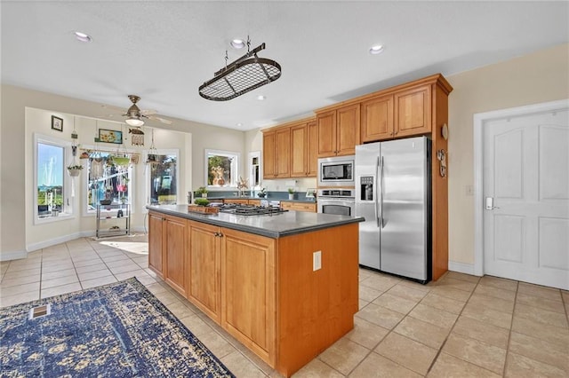 kitchen with a kitchen island, a wealth of natural light, ceiling fan, and stainless steel appliances