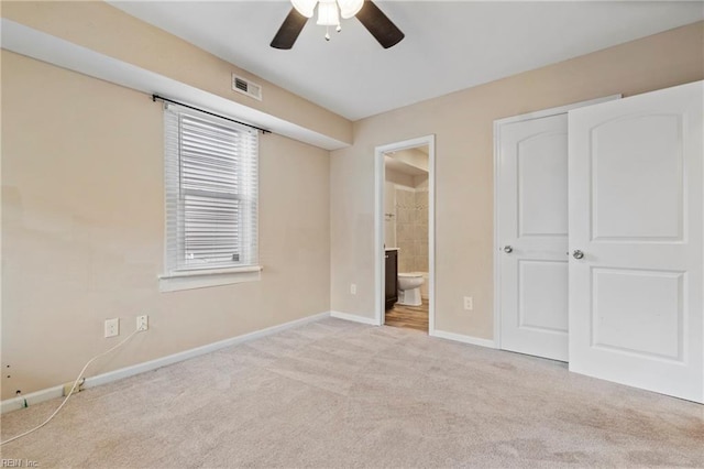 unfurnished bedroom featuring light colored carpet, ceiling fan, and ensuite bath