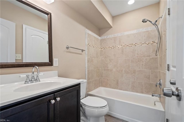 full bathroom featuring tiled shower / bath, vanity, and toilet