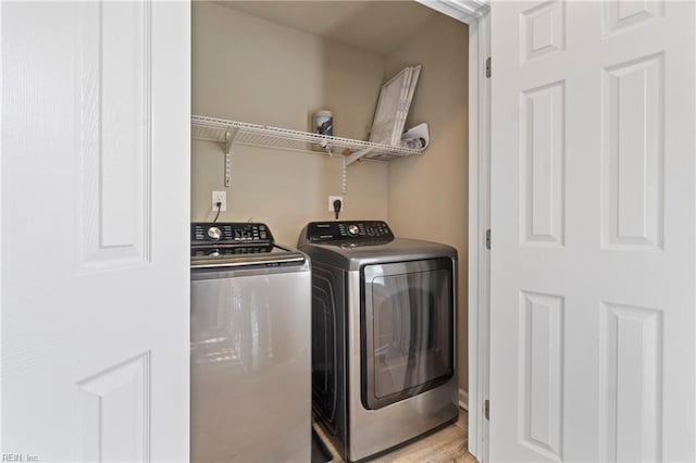 clothes washing area with light hardwood / wood-style flooring and washing machine and dryer