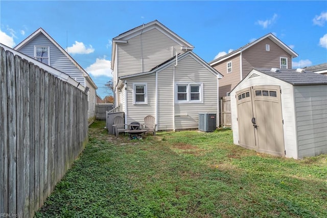 back of house featuring central air condition unit, a storage unit, and a lawn