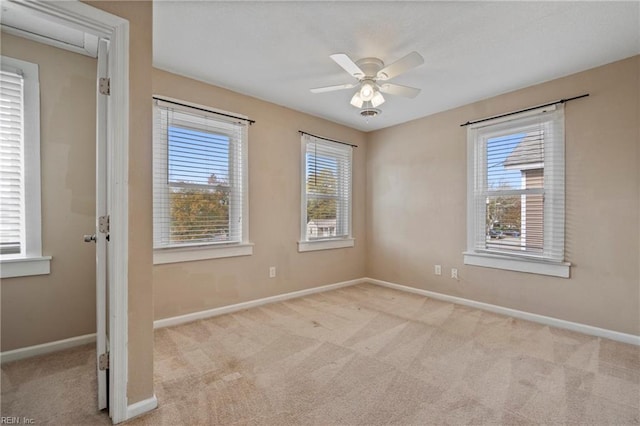 empty room featuring ceiling fan, a wealth of natural light, and light colored carpet