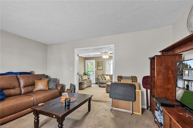 carpeted living room featuring ceiling fan and a textured ceiling