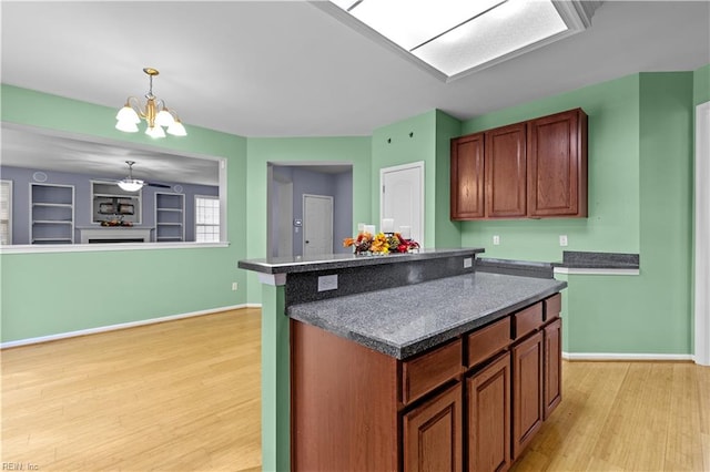 kitchen featuring ceiling fan with notable chandelier, light hardwood / wood-style flooring, a center island, and decorative light fixtures