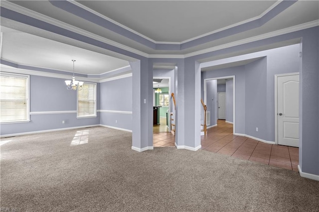 carpeted spare room featuring a raised ceiling, crown molding, and a notable chandelier