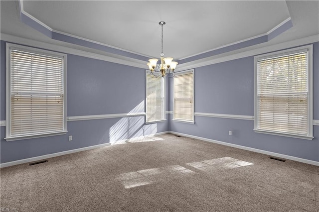 carpeted empty room with plenty of natural light, a raised ceiling, an inviting chandelier, and crown molding