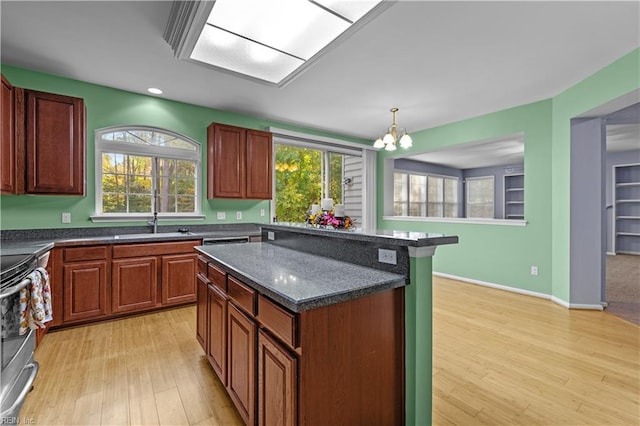 kitchen with hanging light fixtures, stainless steel range oven, a chandelier, a kitchen island, and light wood-type flooring