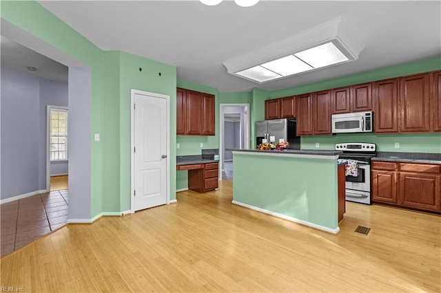 kitchen featuring appliances with stainless steel finishes, a kitchen island, and light hardwood / wood-style flooring