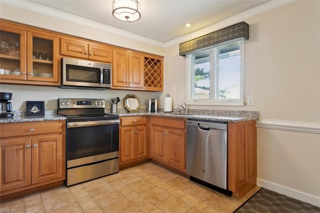 kitchen featuring light stone countertops, sink, appliances with stainless steel finishes, and ornamental molding