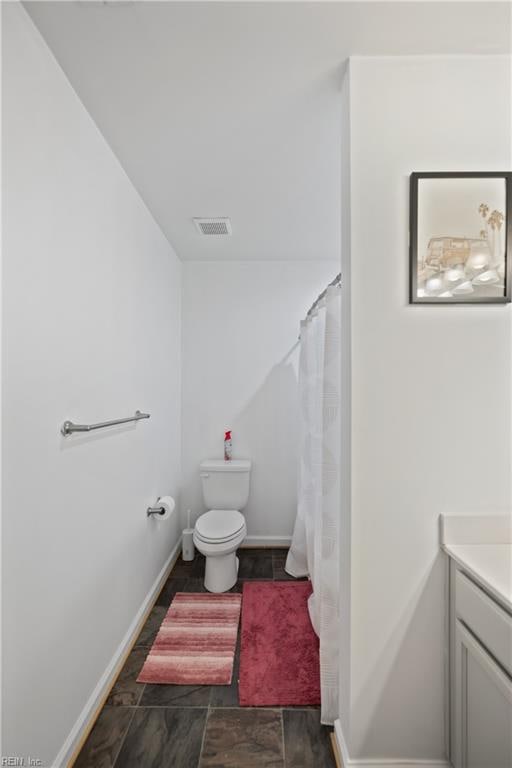 bathroom featuring a shower with shower curtain, vanity, and toilet