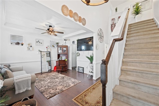 living room with a raised ceiling, ceiling fan, crown molding, and dark hardwood / wood-style floors