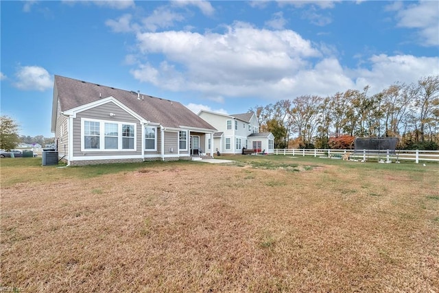 back of house featuring central AC unit and a lawn