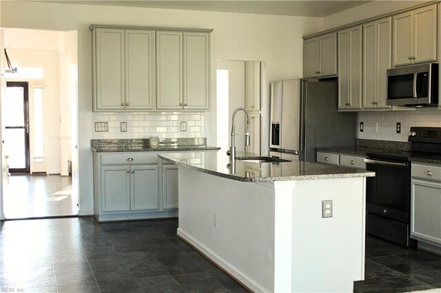 kitchen featuring decorative backsplash, a kitchen island with sink, and appliances with stainless steel finishes