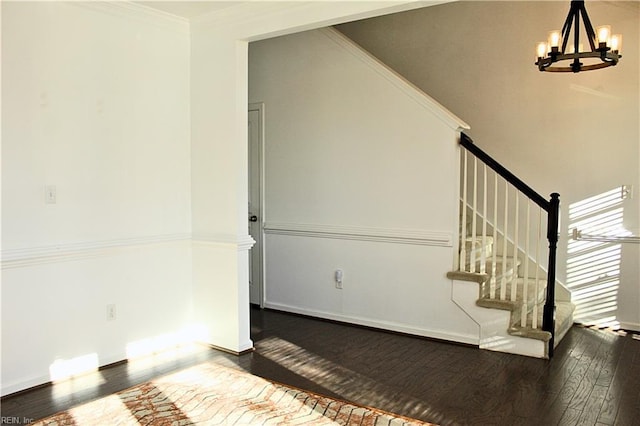 stairs featuring a chandelier, wood-type flooring, and ornamental molding