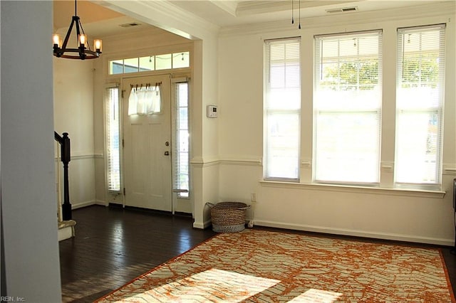 foyer with a chandelier, dark wood-type flooring, and ornamental molding