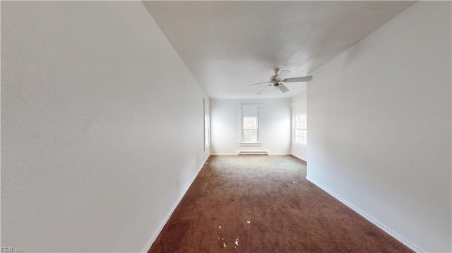 carpeted empty room featuring baseboard heating and ceiling fan