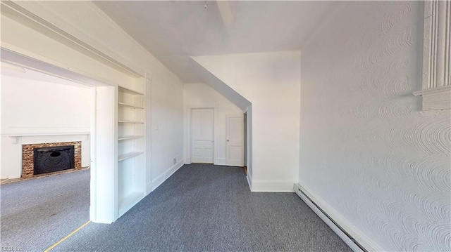 hall featuring built in shelves, dark colored carpet, and a baseboard heating unit