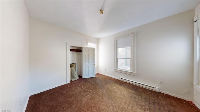 unfurnished bedroom with a closet, dark colored carpet, and a baseboard heating unit