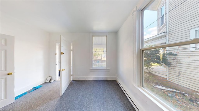 spare room with a baseboard radiator, dark carpet, and plenty of natural light