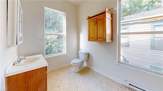 bathroom featuring a baseboard heating unit, a wealth of natural light, vanity, and toilet