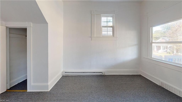 interior space with plenty of natural light, dark carpet, and a baseboard heating unit