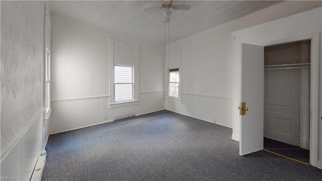 unfurnished bedroom featuring a closet, dark carpet, and ceiling fan