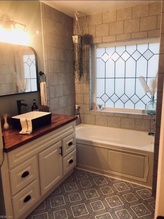 bathroom featuring a wealth of natural light, a bath, and vanity