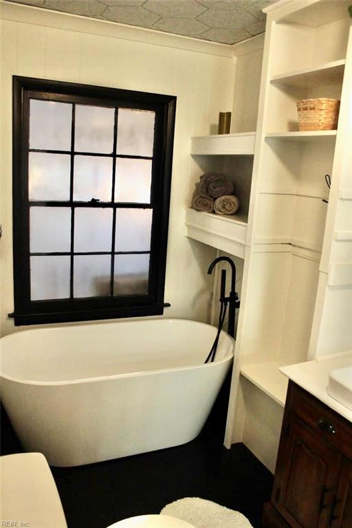 bathroom with a washtub, vanity, and toilet